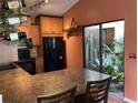 A warm kitchen features wooden cabinets, black appliances, and a view to the patio at 4315 Longshore Dr, Land O Lakes, FL 34639