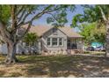 Attractive home with a covered front porch, beautiful lawn, and mature trees on a sunny day at 505 27Th N Ave, St Petersburg, FL 33704