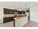 Well-equipped kitchen featuring dark wood cabinetry, granite countertops, stainless steel appliances, and a tile backsplash at 627 Washita Stone Dr, Ruskin, FL 33570