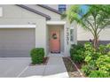 Close up of a charming front entrance with a wreath, green bushes, and a paved walkway at 7331 Canterbury Bells Ct, Tampa, FL 33619