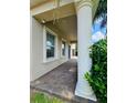 Covered porch featuring brick flooring, a prominent support column, and views of the surrounding greenery at 11936 Sand Myrtle Rd, Riverview, FL 33579