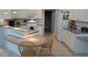 Bright kitchen featuring white cabinets, a breakfast bar, and tiled flooring at 1803 Longview Ln, Tarpon Springs, FL 34689