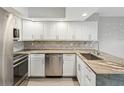 Updated kitchen features white cabinets, stainless appliances, tile backsplash, and granite countertops with ample counter space at 200 Meres Blvd # 26, Tarpon Springs, FL 34689
