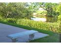 Picturesque backyard featuring a stone bench overlooking a tranquil pond surrounded by vibrant greenery at 208 Villa Dr # 208, Osprey, FL 34229