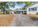 A winding driveway leads to a quaint white home with blue shutters, surrounded by lush greenery and mature trees at 2244 Glenmoor N Rd, Clearwater, FL 33764