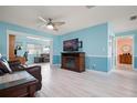 Bright living room with light aqua walls, wood-look tile flooring, and a comfortable seating area at 2859 Thistle N Ct, Palm Harbor, FL 34684