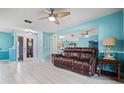 Spacious living room featuring wood-look tile flooring, a leather sofa, and ample natural light at 2859 Thistle N Ct, Palm Harbor, FL 34684