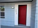 Attractive red front door with fresh white trim, the address, and blue siding on a well maintained home at 3615 Kingsbury Dr, Holiday, FL 34691