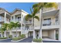Three-story condos with white railings, garages, and palm trees under a bright blue sky at 459 Bahia Beach Blvd, Ruskin, FL 33570
