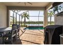 Outdoor patio with a dining table, grill, and a screened enclosure overlooking the pool and lake at 6223 Baywood Ct, Bradenton, FL 34211