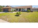 Inviting single-story residence with a stone facade, new solar panels, and well-kept lawn with young palm trees at 7428 Bramblewood Dr, Port Richey, FL 34668