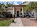 Inviting front porch with seating area, featuring brick accents, decorative plants, and a welcoming entrance at 7850 Lake Placid Ln, New Port Richey, FL 34655