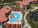 Aerial view of a community pool and patio with lounge chairs and red umbrellas at 2709 Via Cipriani # 522B, Clearwater, FL 33764