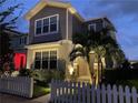 Beautiful two-story home with manicured lawn, picket fence, and professional outdoor lighting illuminating the entrance at 11309 Grand Park Ave, Riverview, FL 33578