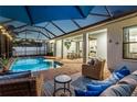 Outdoor living space featuring a screened-in pool, covered patio, and comfortable seating at 13008 Eagles Entry Dr, Odessa, FL 33556