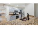 Modern kitchen with stainless steel appliances, granite countertops, double sinks and light gray cabinetry at 1308 W Perdiz St, Tampa, FL 33612