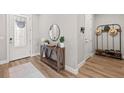 Inviting foyer featuring light walls, wood flooring, a decorative table, and a hall tree at 2577 Buckthorn Loop, North Port, FL 34289