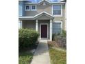 A charming townhome entrance with a red door, covered porch, and pathway for easy access at 3441 Santa Rita Lane, Land O Lakes, FL 34639