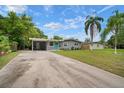 Traditional home showcasing a long driveway, carport, lush green lawn, and tropical palm trees against a bright blue sky at 5115 32Nd N Ave, St Petersburg, FL 33710