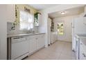 Functional kitchen with white cabinets, dishwasher, and view of the laundry area at 6936 77Th N Ter, Pinellas Park, FL 33781