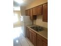 Kitchen features wooden cabinets, a stainless steel double sink, and tile flooring with an adjacent dining area at 7507 Presley Pl # D, Tampa, FL 33617