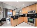 Kitchen with light wood cabinets, stainless steel appliances, black backsplash, and adjacent living space at 777 N Ashley Dr # 1516, Tampa, FL 33602