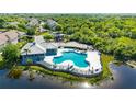 Aerial view of a community pool area with lounge chairs, umbrellas, and landscaping near a small lake at 9516 Amberdale Ct # 202, Riverview, FL 33569