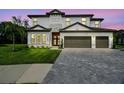 Elegant two-story home featuring a stone facade, a well-manicured lawn, and a spacious three-car garage at 12409 Gentle Swan Pl, Odessa, FL 33556