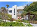 Stylish home featuring a second-story balcony and patio with seating, surrounded by lush greenery at 2003 Gulf Way, St Pete Beach, FL 33706