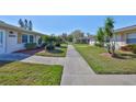 Neighborhood street view of the home featuring lush landscaping and green grass at 2202 Clubhouse Dr # 174, Sun City Center, FL 33573