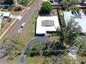 An aerial view of a white, single-story home with a dark driveway and nearby red brick road and mature trees at 500 Oleander S Way, St Petersburg, FL 33707