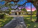 Well-maintained single-story home featuring a spacious driveway and mature trees in a landscaped yard at 500 Oleander S Way, St Petersburg, FL 33707