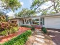 Beautiful single-story home with lush greenery, featuring a red deck and stone walkway at 5533 97Th N Way, St Petersburg, FL 33708