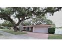 Lovely single-story home featuring mature landscaping and a brick driveway leading to the garage at 1001 Brookside Dr, Clearwater, FL 33764