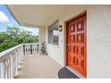 A cozy porch featuring a red door, white railings, and a view of lush greenery at 1012 Pearce Dr # 304, Clearwater, FL 33764