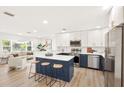 Open concept kitchen with white cabinets, stainless appliances, and breakfast bar that leads to a cozy living room at 1410 San Charles Dr, Dunedin, FL 34698
