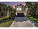 Charming two-story home with a well-manicured lawn and mature palm trees during a colorful sunset at 1626 Tallulah Ter, Wesley Chapel, FL 33543