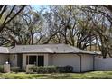 A side view of a home with a well-maintained lawn, lush greenery, and a white privacy fence at 2105 Curry Rd, Lutz, FL 33549