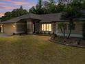 Dusk view of a well-maintained home featuring manicured landscaping and a spacious lawn at 3171 Roxmere Dr, Palm Harbor, FL 34685