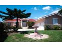 Charming home featuring a well-manicured lawn, fountain, and a covered front entrance with columns at 320 Bath Club Blvd S, North Redington Beach, FL 33708