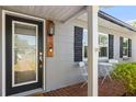 Beautiful front entryway featuring a black trimmed glass door, grey siding, and brick porch at 3614 S Lois Ave, Tampa, FL 33629