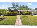 Charming single-story home with well-manicured lawn, walkway, and mature trees on a sunny day at 3614 S Lois Ave, Tampa, FL 33629