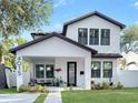 Charming two-story home with white stucco, dark trim, manicured lawn, and inviting covered front porch at 4015 10Th N Ave, St Petersburg, FL 33713
