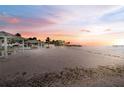 Scenic beach view featuring pristine sand, palm trees, and covered picnic areas at sunset at 6241 Bayside Dr, New Port Richey, FL 34652