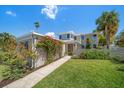 Charming two-story home with lush green lawn, mature landscaping and inviting walkway to the front door at 785 Bay Esplanade, Clearwater Beach, FL 33767
