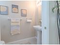 Cozy half-bathroom featuring a pedestal sink, decorative wall art, and neutral color palette at 9807 Carlsdale Dr, Riverview, FL 33578