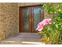 Elegant double front doors framed by vibrant flowers and brick facade create a welcoming entrance at 1203 Parrilla De Avila, Tampa, FL 33613