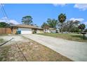 Long concrete driveway leading to a single-story home with stone accents and a detached garage at 1371 Meredith Dr, Spring Hill, FL 34608