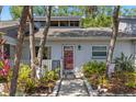 Charming single-story home featuring a red front door, gray exterior, and lovely landscaping with decorative accents at 20 Iris Pl, Oldsmar, FL 34677