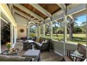 Inviting screened porch with wicker furniture, ceiling fan, and a beautiful view of the landscaped backyard at 20 Iris Pl, Oldsmar, FL 34677